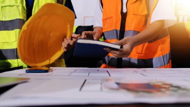 Endüstriyel mühendislerden oluşan bir ekip, fabrikadaki masada bulunan makine planlarını analiz ediyor. Fabrikada ya da üretim tesisinde çalışıyorum..