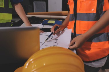 Endüstriyel mühendislerden oluşan bir ekip, fabrikadaki masada bulunan makine planlarını analiz ediyor. Fabrikada ya da üretim tesisinde çalışıyorum..