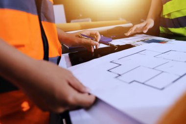 Endüstriyel mühendislerden oluşan bir ekip, fabrikadaki masada bulunan makine planlarını analiz ediyor. Fabrikada ya da üretim tesisinde çalışıyorum..