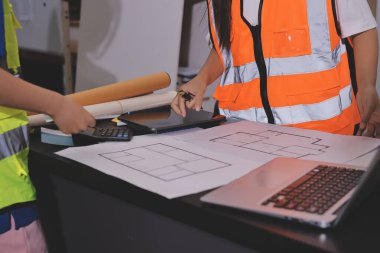 Endüstriyel mühendislerden oluşan bir ekip, fabrikadaki masada bulunan makine planlarını analiz ediyor. Fabrikada ya da üretim tesisinde çalışıyorum..