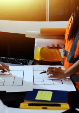 Endüstriyel mühendislerden oluşan bir ekip, fabrikadaki masada bulunan makine planlarını analiz ediyor. Fabrikada ya da üretim tesisinde çalışıyorum..