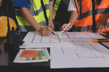 Endüstriyel mühendislerden oluşan bir ekip, fabrikadaki masada bulunan makine planlarını analiz ediyor. Fabrikada ya da üretim tesisinde çalışıyorum..