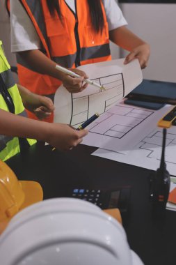 Endüstriyel mühendislerden oluşan bir ekip, fabrikadaki masada bulunan makine planlarını analiz ediyor. Fabrikada ya da üretim tesisinde çalışıyorum..