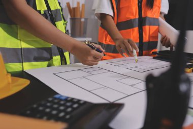 Endüstriyel mühendislerden oluşan bir ekip, fabrikadaki masada bulunan makine planlarını analiz ediyor. Fabrikada ya da üretim tesisinde çalışıyorum..