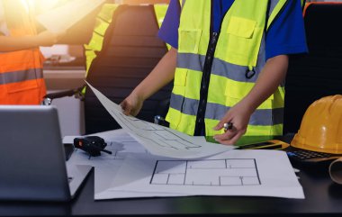 Endüstriyel mühendislerden oluşan bir ekip, fabrikadaki masada bulunan makine planlarını analiz ediyor. Fabrikada ya da üretim tesisinde çalışıyorum..