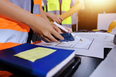 Endüstriyel mühendislerden oluşan bir ekip, fabrikadaki masada bulunan makine planlarını analiz ediyor. Fabrikada ya da üretim tesisinde çalışıyorum..