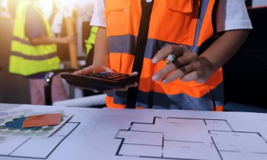 Endüstriyel mühendislerden oluşan bir ekip, fabrikadaki masada bulunan makine planlarını analiz ediyor. Fabrikada ya da üretim tesisinde çalışıyorum..