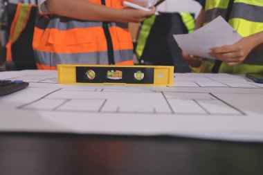 Endüstriyel mühendislerden oluşan bir ekip, fabrikadaki masada bulunan makine planlarını analiz ediyor. Fabrikada ya da üretim tesisinde çalışıyorum..