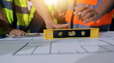 Endüstriyel mühendislerden oluşan bir ekip, fabrikadaki masada bulunan makine planlarını analiz ediyor. Fabrikada ya da üretim tesisinde çalışıyorum..