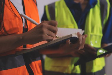 Endüstriyel mühendislerden oluşan bir ekip, fabrikadaki masada bulunan makine planlarını analiz ediyor. Fabrikada ya da üretim tesisinde çalışıyorum..