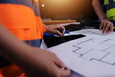 Endüstriyel mühendislerden oluşan bir ekip, fabrikadaki masada bulunan makine planlarını analiz ediyor. Fabrikada ya da üretim tesisinde çalışıyorum..