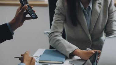 Genç iş kadını ofiste otururken dizüstü bilgisayar kullanıyor..