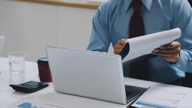 Modern ofiste dizüstü bilgisayar kullanan ve finansal verileri analiz eden bir iş adamı