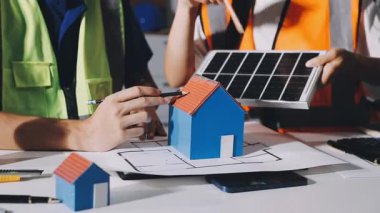 Evde çalışan genç bayan mühendis ve masanın üzerinde bir plan var..