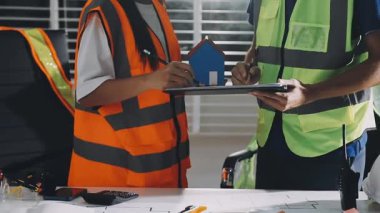 Genç Asyalı mühendis, fabrikadaki iş arkadaşıyla panoyu kontrol ediyor.