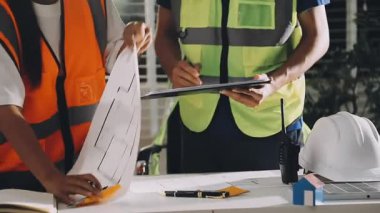 İnşaat işçileri planlarını inşaat alanındaki planlarla tartışıyor..