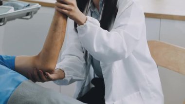 Doktor klinikte hasta bileklerini kontrol ediyor.