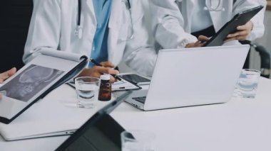 Tıp alanında çalışan bir grup genç modern ofis masasında otururken tablet bilgisayar kullanıyor.