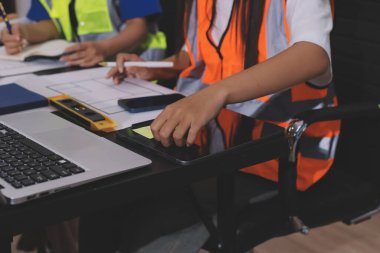 Endüstriyel mühendislerden oluşan bir ekip, fabrikadaki masada bulunan makine planlarını analiz ediyor. Fabrikada ya da üretim tesisinde çalışıyorum..