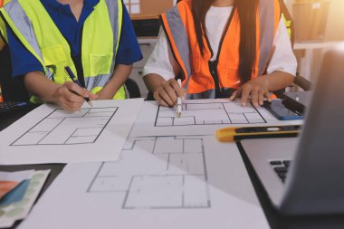 Endüstriyel mühendislerden oluşan bir ekip, fabrikadaki masada bulunan makine planlarını analiz ediyor. Fabrikada ya da üretim tesisinde çalışıyorum..