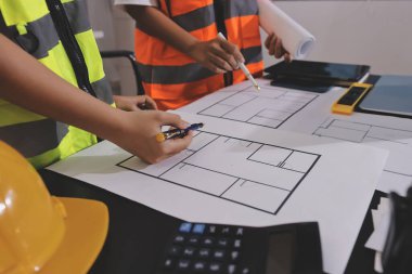 Endüstriyel mühendislerden oluşan bir ekip, fabrikadaki masada bulunan makine planlarını analiz ediyor. Fabrikada ya da üretim tesisinde çalışıyorum..