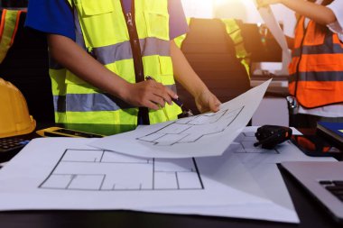 Endüstriyel mühendislerden oluşan bir ekip, fabrikadaki masada bulunan makine planlarını analiz ediyor. Fabrikada ya da üretim tesisinde çalışıyorum..