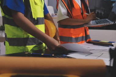 Endüstriyel mühendislerden oluşan bir ekip, fabrikadaki masada bulunan makine planlarını analiz ediyor. Fabrikada ya da üretim tesisinde çalışıyorum..