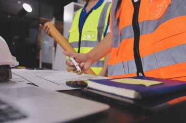 Endüstriyel mühendislerden oluşan bir ekip, fabrikadaki masada bulunan makine planlarını analiz ediyor. Fabrikada ya da üretim tesisinde çalışıyorum..