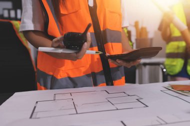 Endüstriyel mühendislerden oluşan bir ekip, fabrikadaki masada bulunan makine planlarını analiz ediyor. Fabrikada ya da üretim tesisinde çalışıyorum..