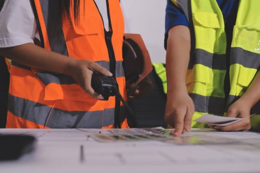 Endüstriyel mühendislerden oluşan bir ekip, fabrikadaki masada bulunan makine planlarını analiz ediyor. Fabrikada ya da üretim tesisinde çalışıyorum..