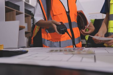 Endüstriyel mühendislerden oluşan bir ekip, fabrikadaki masada bulunan makine planlarını analiz ediyor. Fabrikada ya da üretim tesisinde çalışıyorum..