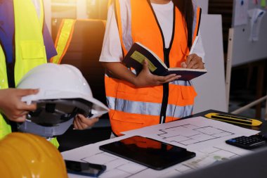 Endüstriyel mühendislerden oluşan bir ekip, fabrikadaki masada bulunan makine planlarını analiz ediyor. Fabrikada ya da üretim tesisinde çalışıyorum..