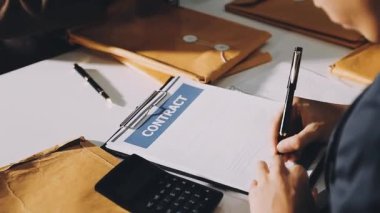 Beyaz gömlekli ve mavi ceketli bir adam. Kalem ve kalemle ahşap bir masada deftere yazıyor.