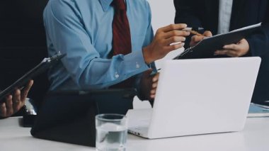 Genç iş adamları modern ofiste dizüstü bilgisayarla çalışıyorlar..