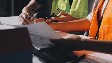 Genç Asyalı bir kadın planlar üzerinde çalışıyor, planlar ve dizüstü bilgisayarlarla çalışıyor, seçici yumuşak odak, klasik hafif ton