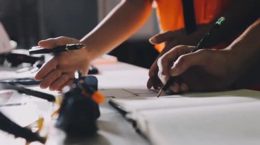 Bir adamın eline, elinde kalemle defterine yazı yazarken yaklaş.