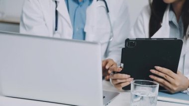 İki doktorun elleri dizüstü bilgisayarda tıbbi reçeteyi tartışıyor.