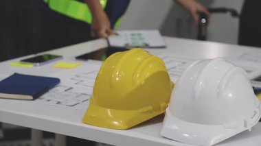 İnşaat alanında miğfer ve dizüstü bilgisayarla çalışan mühendis.