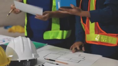 İnşaat mühendisi ya da mimar mühendisi ya da mimarın inşaat alanındaki ya da evindeki planları. İş yerindeki inşaat masasında miğferi ve planı olan mühendis.