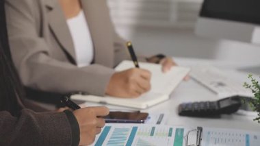 Genç iş kadını modern ofiste çalışırken deftere notlar yazıyor, kapat -