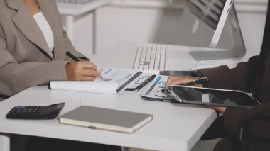 Genç bayan ofiste çalışırken kağıda yazı yazıyor..