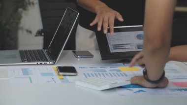 İş kadını elinde tablet tutuyor, çizelgeleri gösteriyor ve bir raporu analiz ediyor.