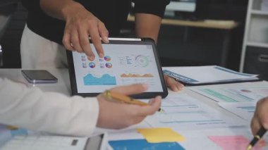 Meslektaşları olan bir iş kadını tableti işaret ediyor