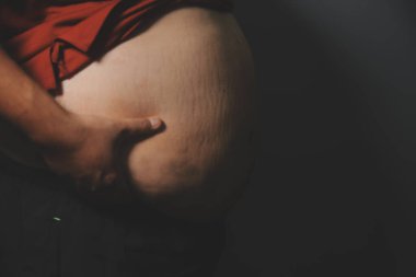 Asyalı şişman bir adam aynanın önünde vücuduna bakıyor. Aşırı göbek yağı, sağlıksız yaşam tarzı, diyet konsepti.