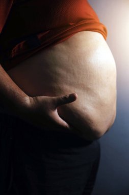 Asyalı şişman bir adam aynanın önünde vücuduna bakıyor. Aşırı göbek yağı, sağlıksız yaşam tarzı, diyet konsepti.