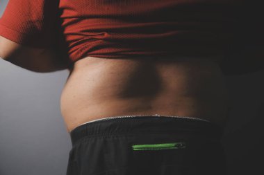 Asyalı şişman bir adam aynanın önünde vücuduna bakıyor. Aşırı göbek yağı, sağlıksız yaşam tarzı, diyet konsepti.