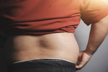 Asyalı şişman bir adam aynanın önünde vücuduna bakıyor. Aşırı göbek yağı, sağlıksız yaşam tarzı, diyet konsepti.