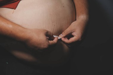 Asyalı şişman bir adam aynanın önünde vücuduna bakıyor. Aşırı göbek yağı, sağlıksız yaşam tarzı, diyet konsepti.