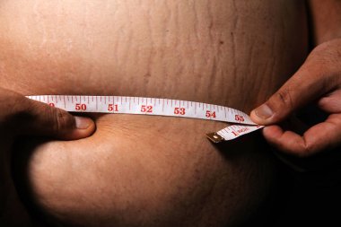 Asyalı şişman bir adam aynanın önünde vücuduna bakıyor. Aşırı göbek yağı, sağlıksız yaşam tarzı, diyet konsepti.