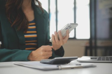 Asyalı iş kadını dizüstü bilgisayar kullanıyor ve ofiste hesap makinesi ile çalışıyor, mali raporu, iş planı yatırımını, mali analiz konseptini analiz etmeyi planlıyor..